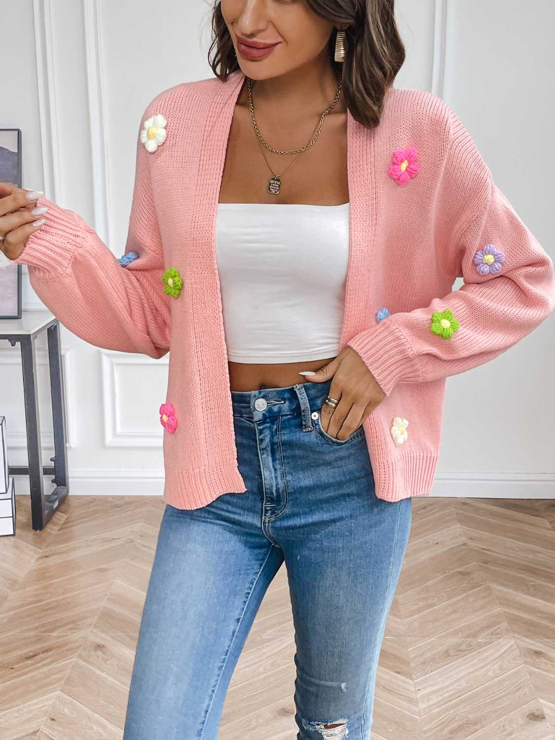 Pink knit cardigan with embroidered multicolor flowers, open front, long sleeves.
