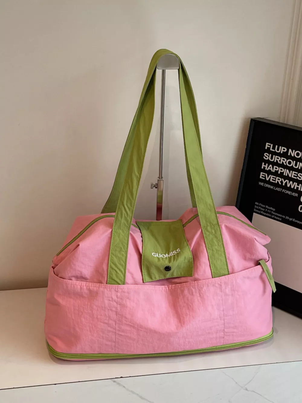 Pink and green two-tone nylon travel bag with green straps and pocket.