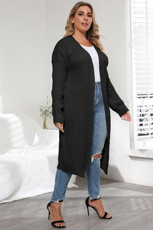 Black oversized knit maxi cardigan with V-neck and long sleeves, styled with jeans and heels.