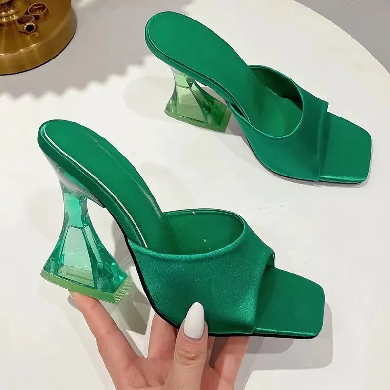 Dark green satin mules with sculpted clear heels and square toe.
