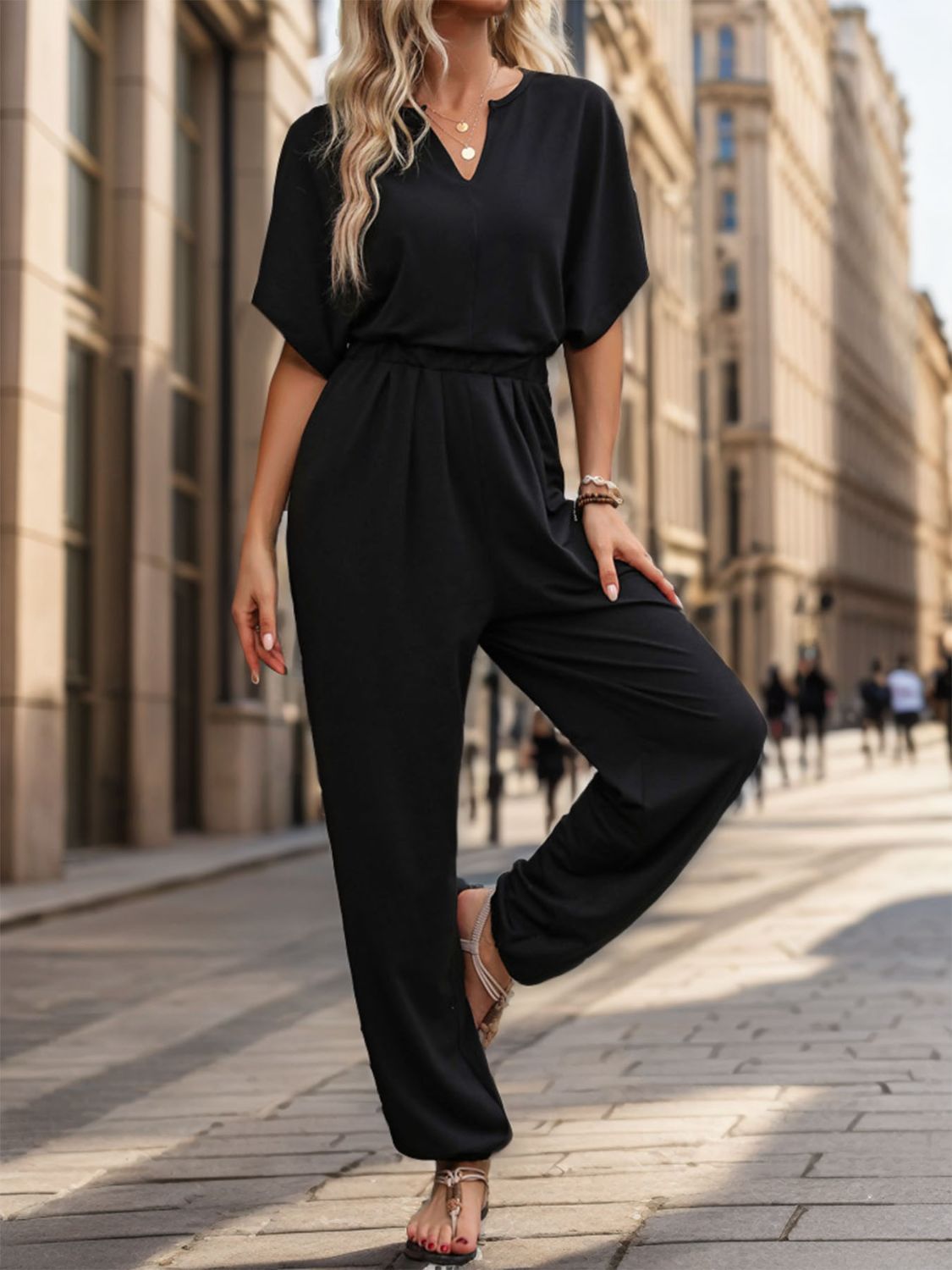 Black V-neck short sleeve jumpsuit with elastic waist and draped wide legs.