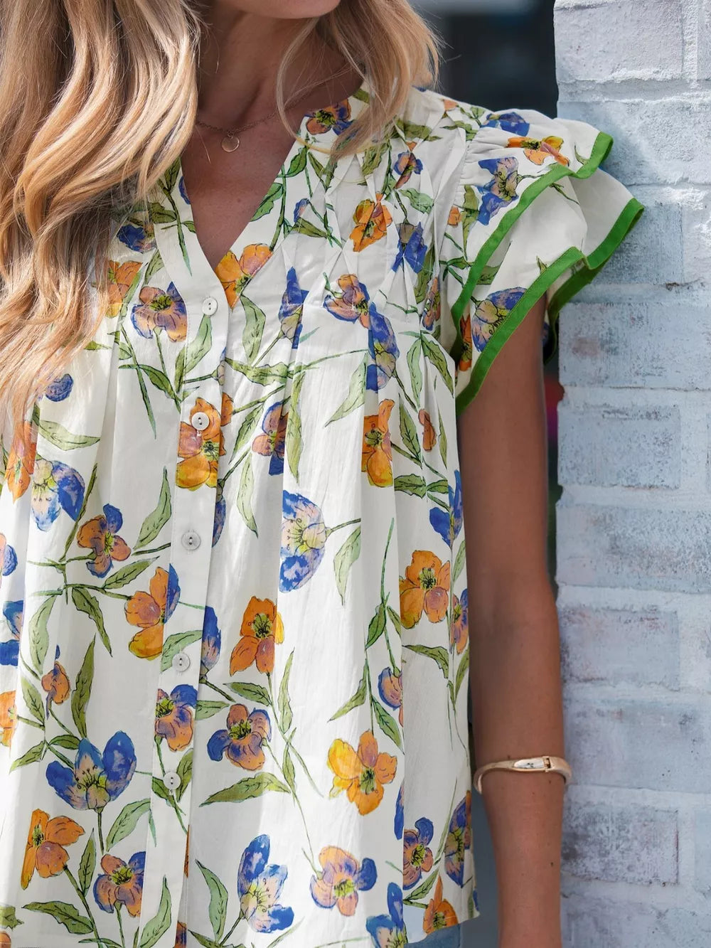 Cotton shirt with vibrant floral print, V-neck, and ruffled sleeves with green trim.
