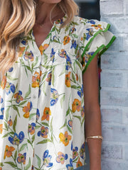 Cotton shirt with vibrant floral print, V-neck, and ruffled sleeves with green trim.