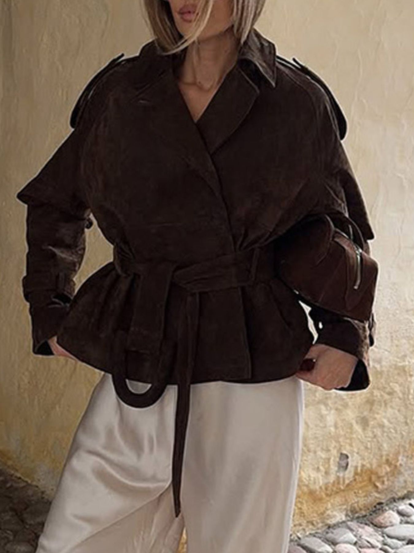 Brown belted trench coat with lapel collar and tie waist.