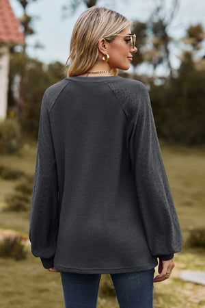 Dark Gray waffle knit raglan sweater with laser cut diamond pattern sleeves.