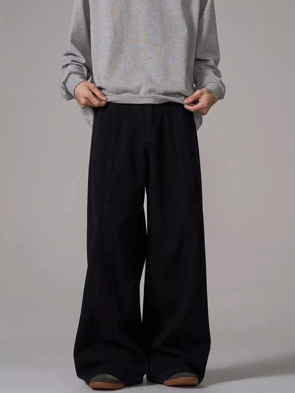 Black wide-leg sweatpants with pockets and a relaxed fit, styled with a grey sweatshirt.