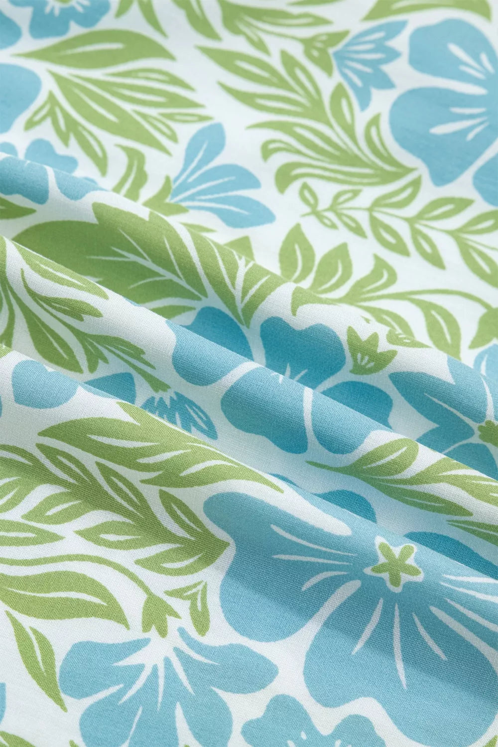 Charming floral mini dress fabric with blue flowers and green leaves on white.