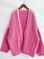 Pink oversized knit cardigan with white contrast stitching and open front.