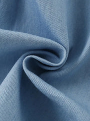 Light blue denim fabric detail of a baby dress with subtle texture.