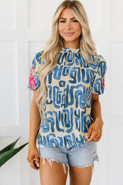 Women's abstract print puff sleeve top with mock neck and embroidered floral detail on sleeves.