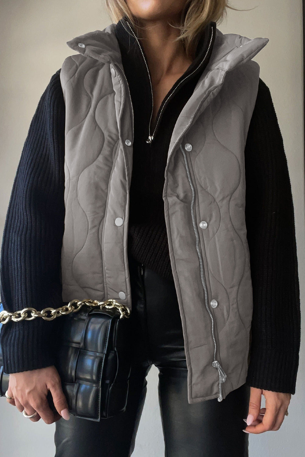 Quilted stand-collar utility gilet in Dust Storm with zip and snap closure, worn over a black sweater.
