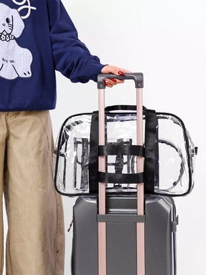 Chic clear PVC travel bag with pink accents and black straps, resting on a suitcase.