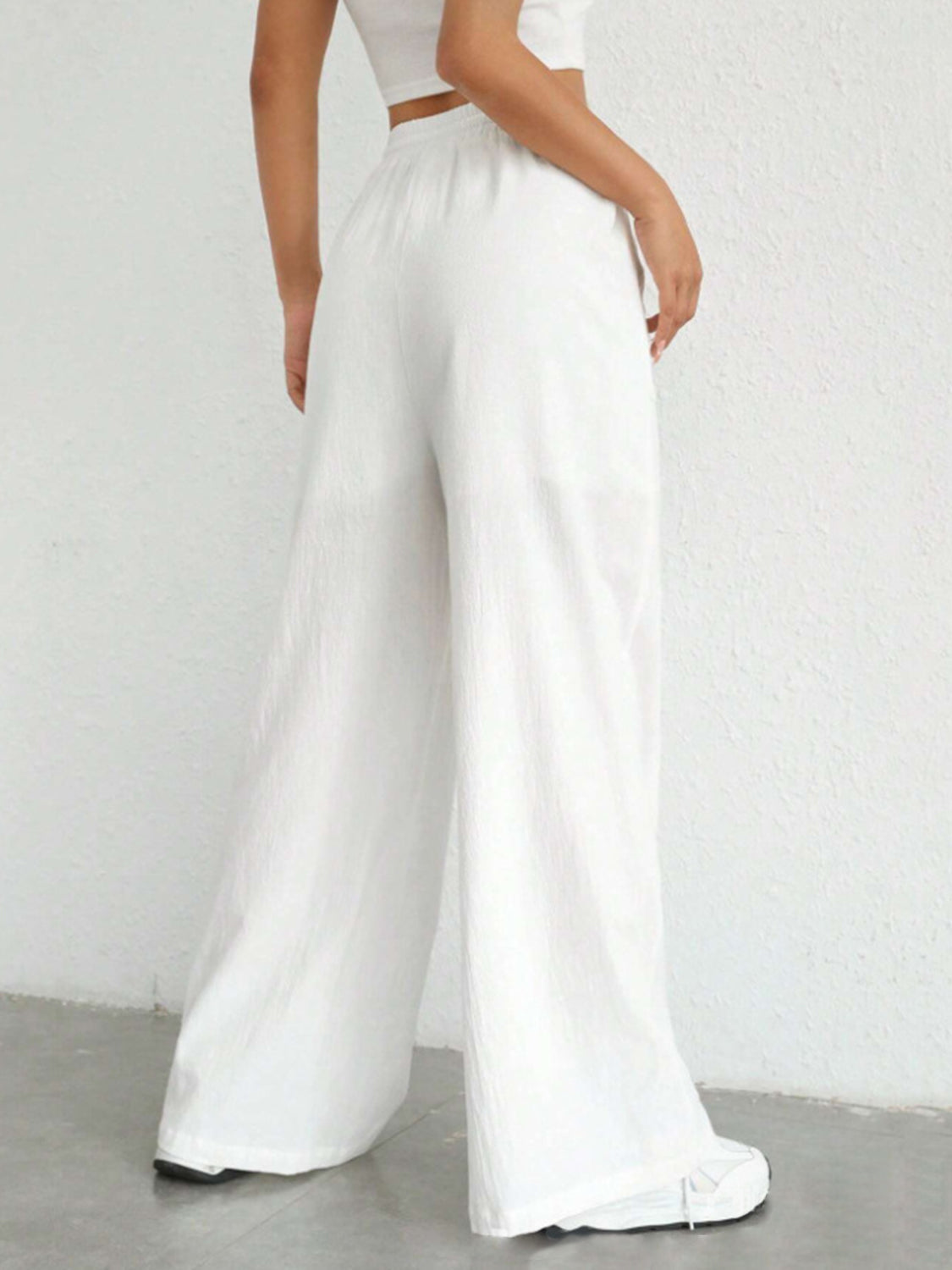 White linen wide-leg drawstring trousers with a relaxed fit.