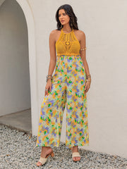 Gold crochet halter jumpsuit with a vibrant floral print and wide palazzo legs.