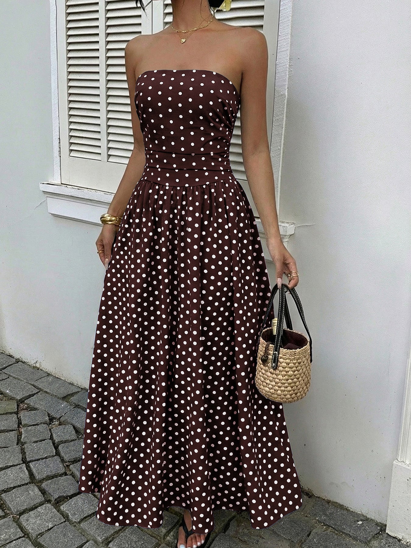 Brown polka dot A-line maxi dress with strapless neckline and cinched waist.