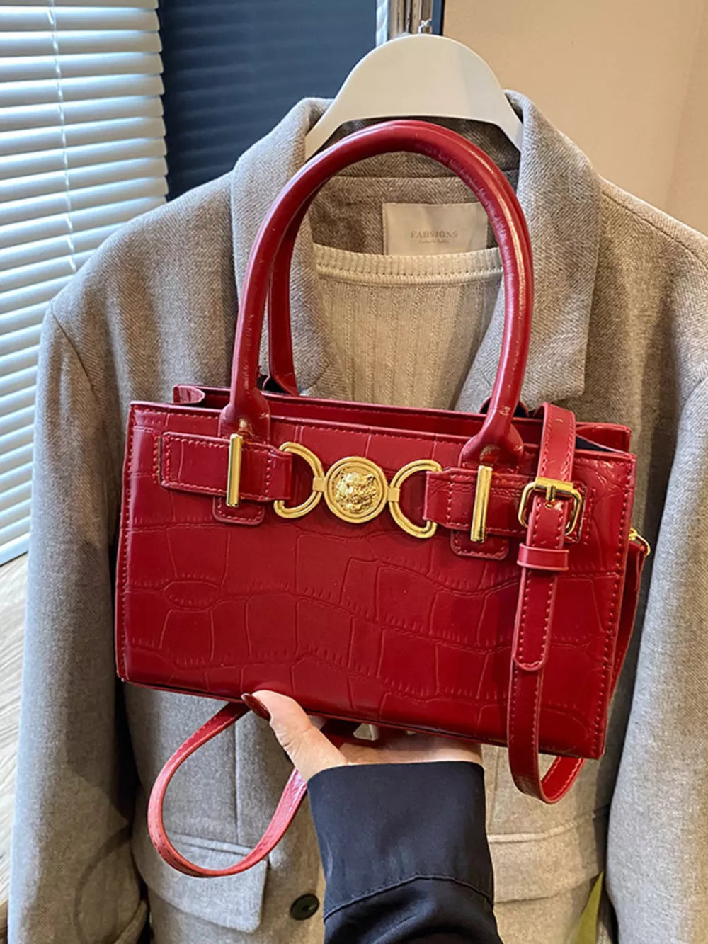 Red crocodile-textured crossbody bag with gold hardware and top handles.
