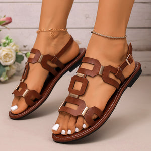 Brown cutout flat sandals with gold hardware and ankle strap.