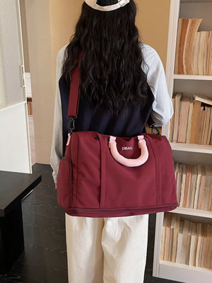 Burgundy nylon travel duffel bag with padded handles and detachable strap.