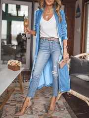 Blue velvet duster coat with fluid silhouette, open front, long sleeves, worn with jeans and heels.