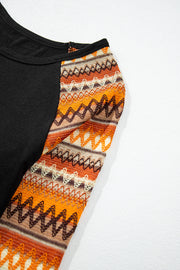 Black raglan tee with orange, brown, and cream Aztec patterned sleeves.