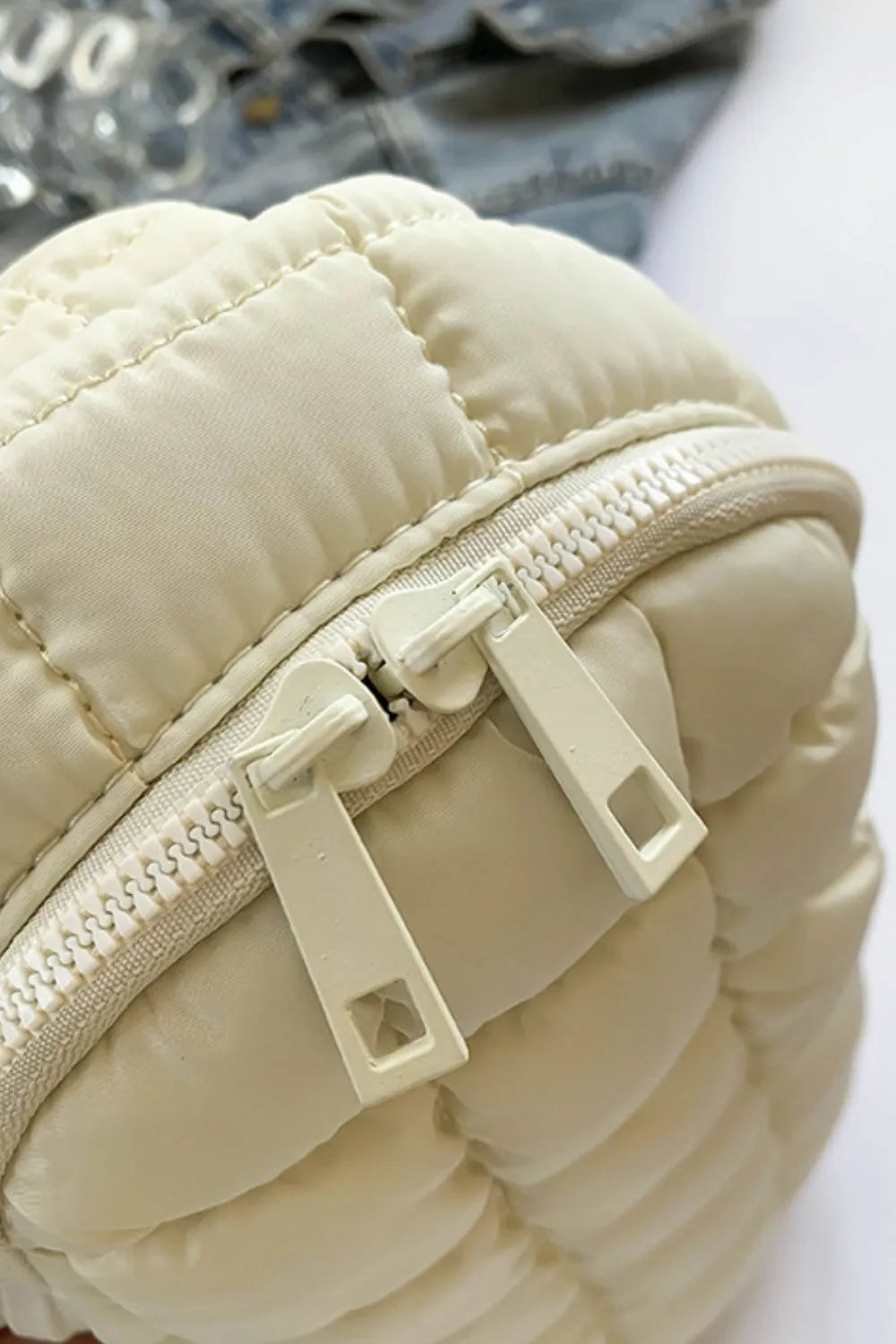 Padded sling bag in Ivory with quilted detail and double zippers.