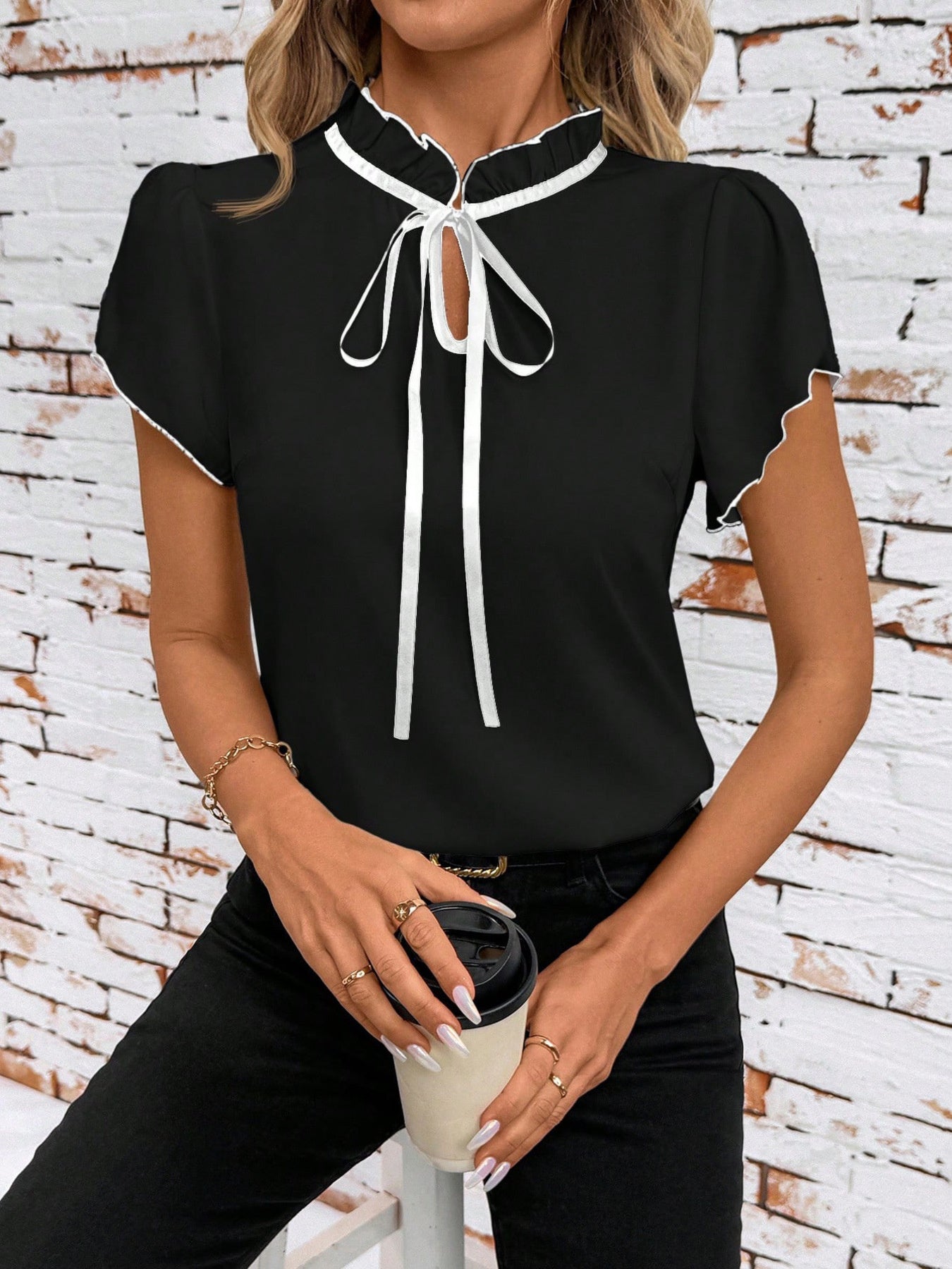 Black maternity blouse with frilled tie-neck and white trim, short sleeves.