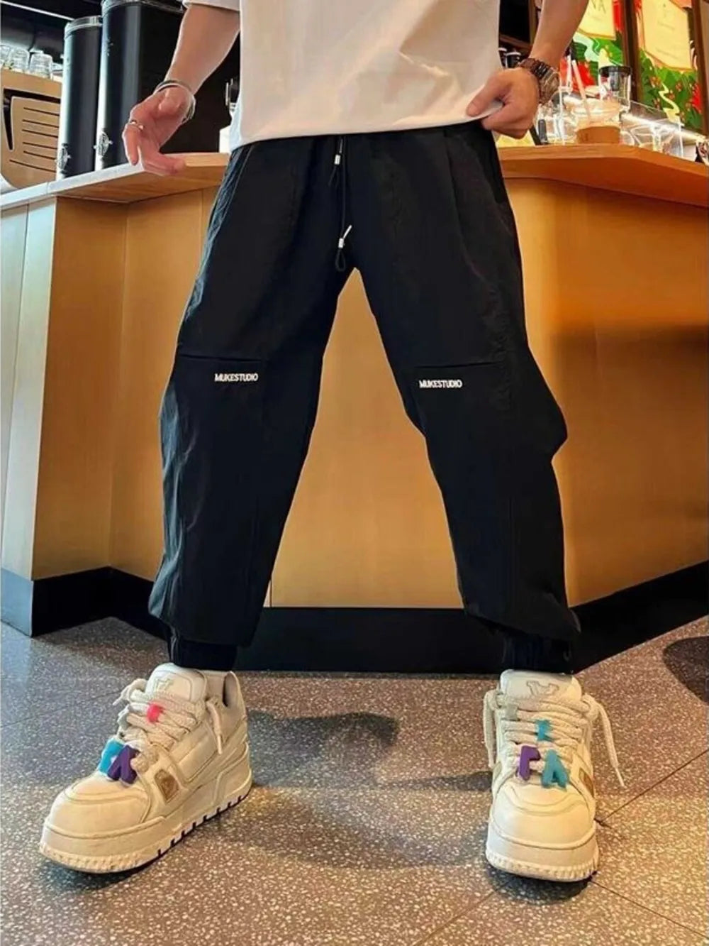 Black cotton joggers with zippered pockets and white logo detail.