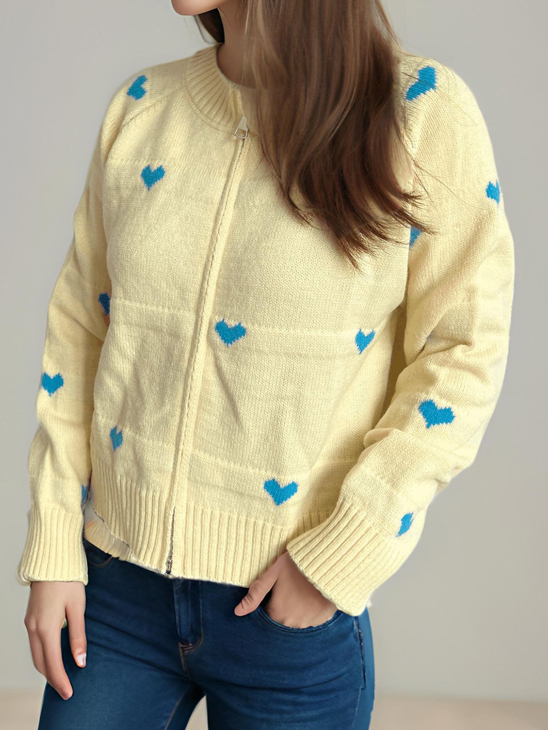 Pastel yellow zip-through knit cardigan with blue heart appliqué and ribbed cuffs.