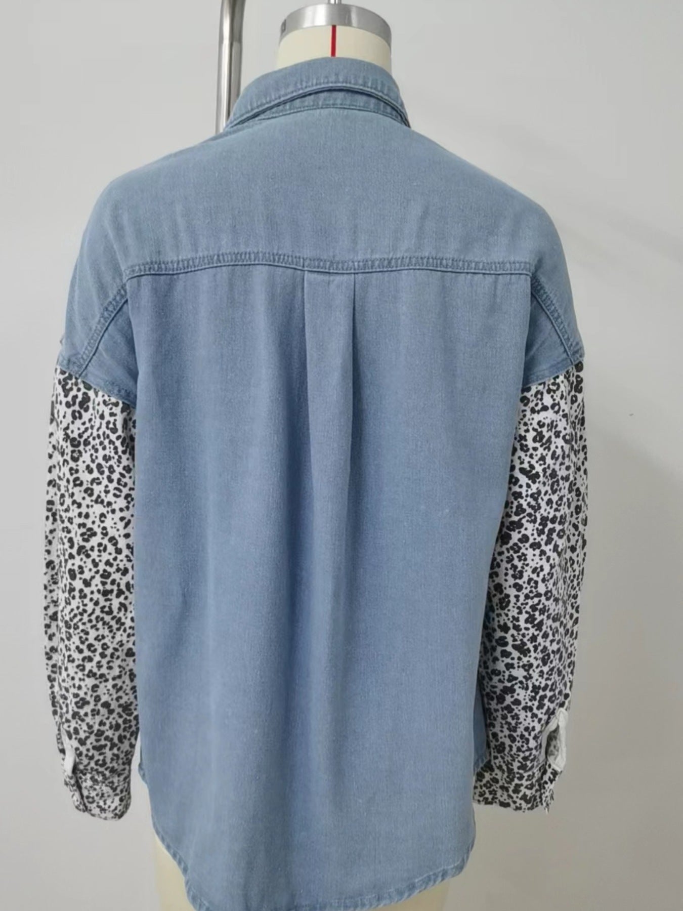 Denim shirt with leopard print sleeves, button-up style, and pockets.