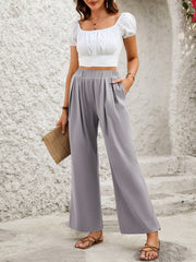 Gray wide leg trousers with elastic waist and pleats, styled with a white crop top.