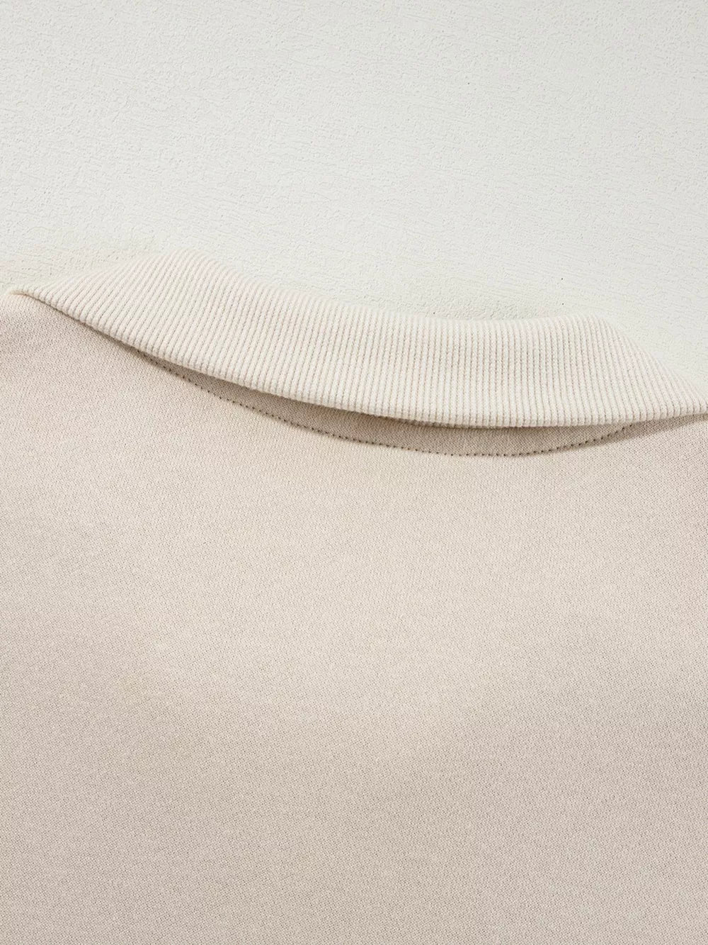 Beige cotton zip-up jacket detail with ribbed collar and comfortable fabric.