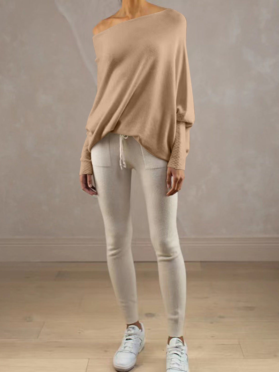 Off-shoulder drape knit sweater in cream with textured cuffs, paired with cream leggings.