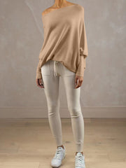 Off-shoulder drape knit sweater in cream with textured cuffs, paired with cream leggings.