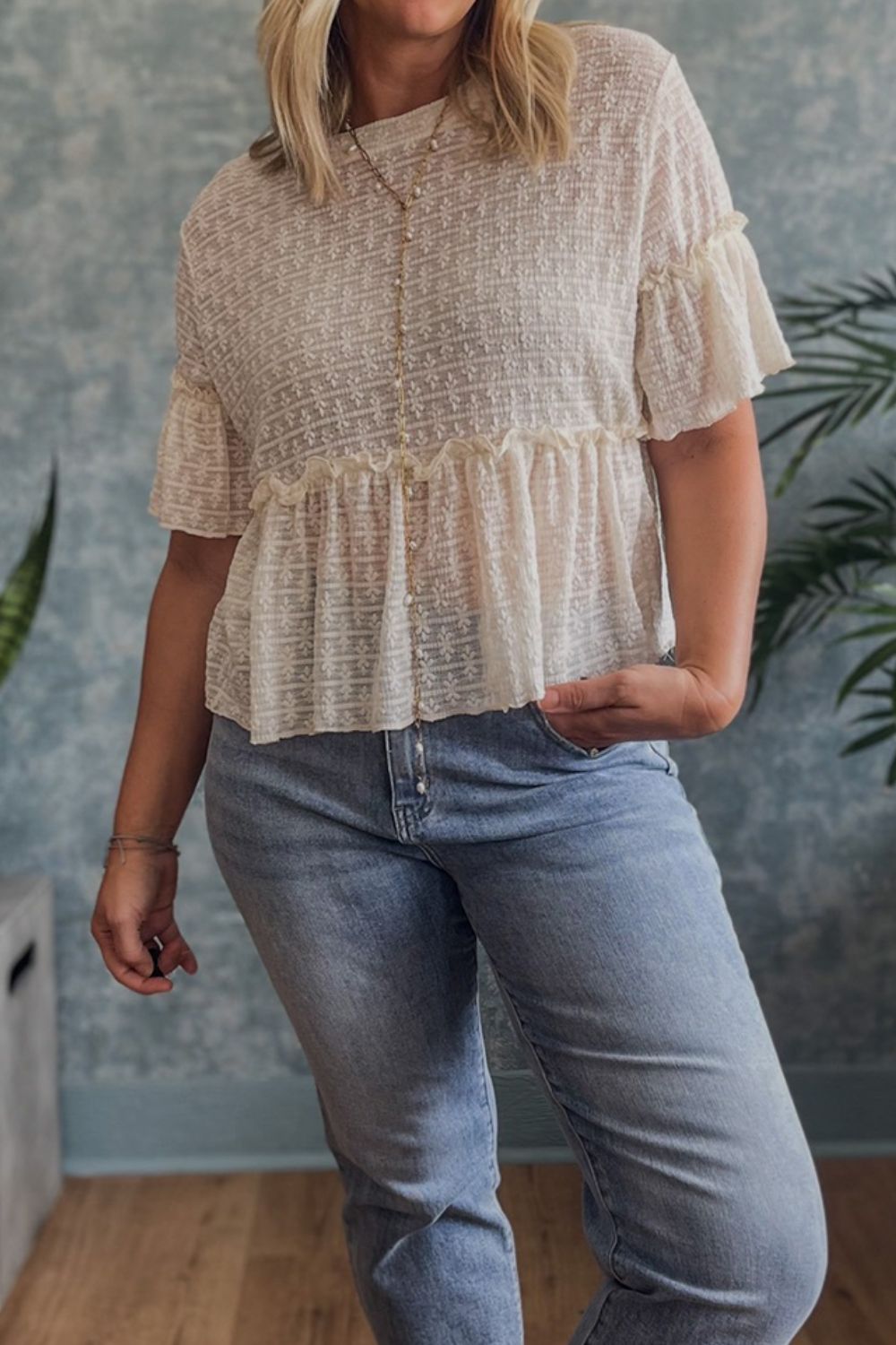 Beige textured blouse with ruffle hemline and short flutter sleeves, button front detail.