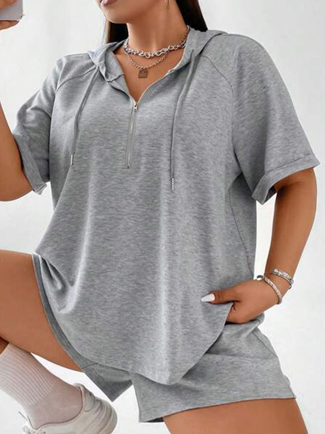 Gray short sleeve hoodie with quarter zip and drawstring, paired with matching shorts.