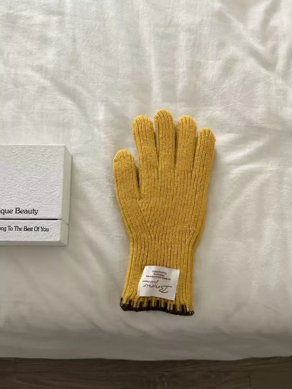 Yellow ribbed knit gloves with scalloped cuff and dark trim detail.