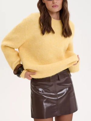 Cozy knit sweater in pastel yellow with relaxed fit and crew neck, styled with a patent skirt.