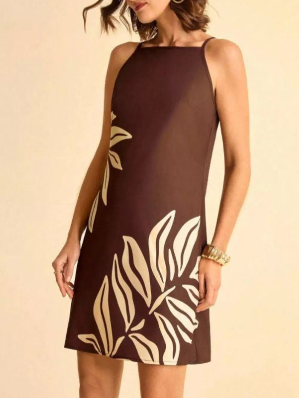 Brown mini dress with cream tropical leaf print, square neck, and spaghetti straps.