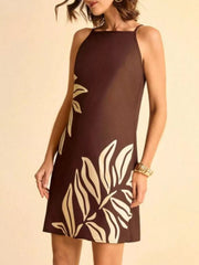 Brown mini dress with cream tropical leaf print, square neck, and spaghetti straps.