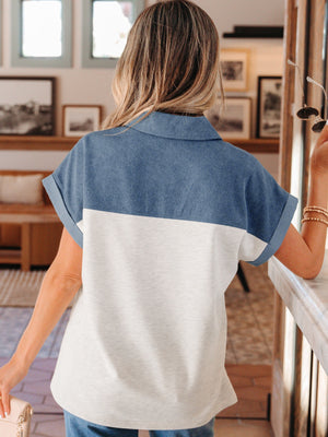 Two-tone denim polo shirt with collar, short sleeves, and color-block detail.