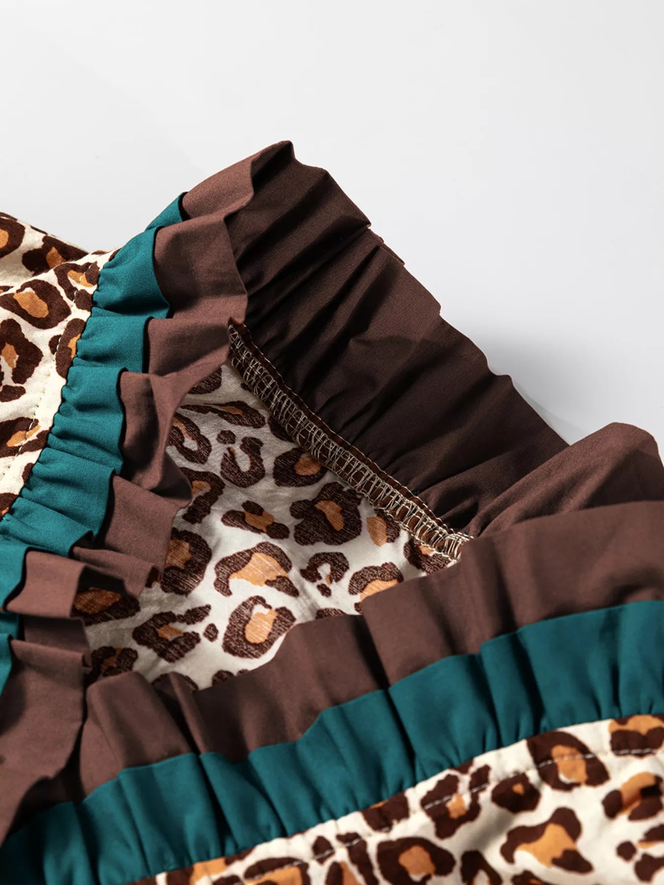 Leopard print button-down shirt with brown and teal frilled trim detail.