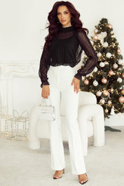 Black sheer mock neck blouse with textured dots and ruffled cuffs.