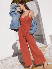 Orange-red tie-strap bodice wide-leg jumpsuit with smocked waist and pockets.