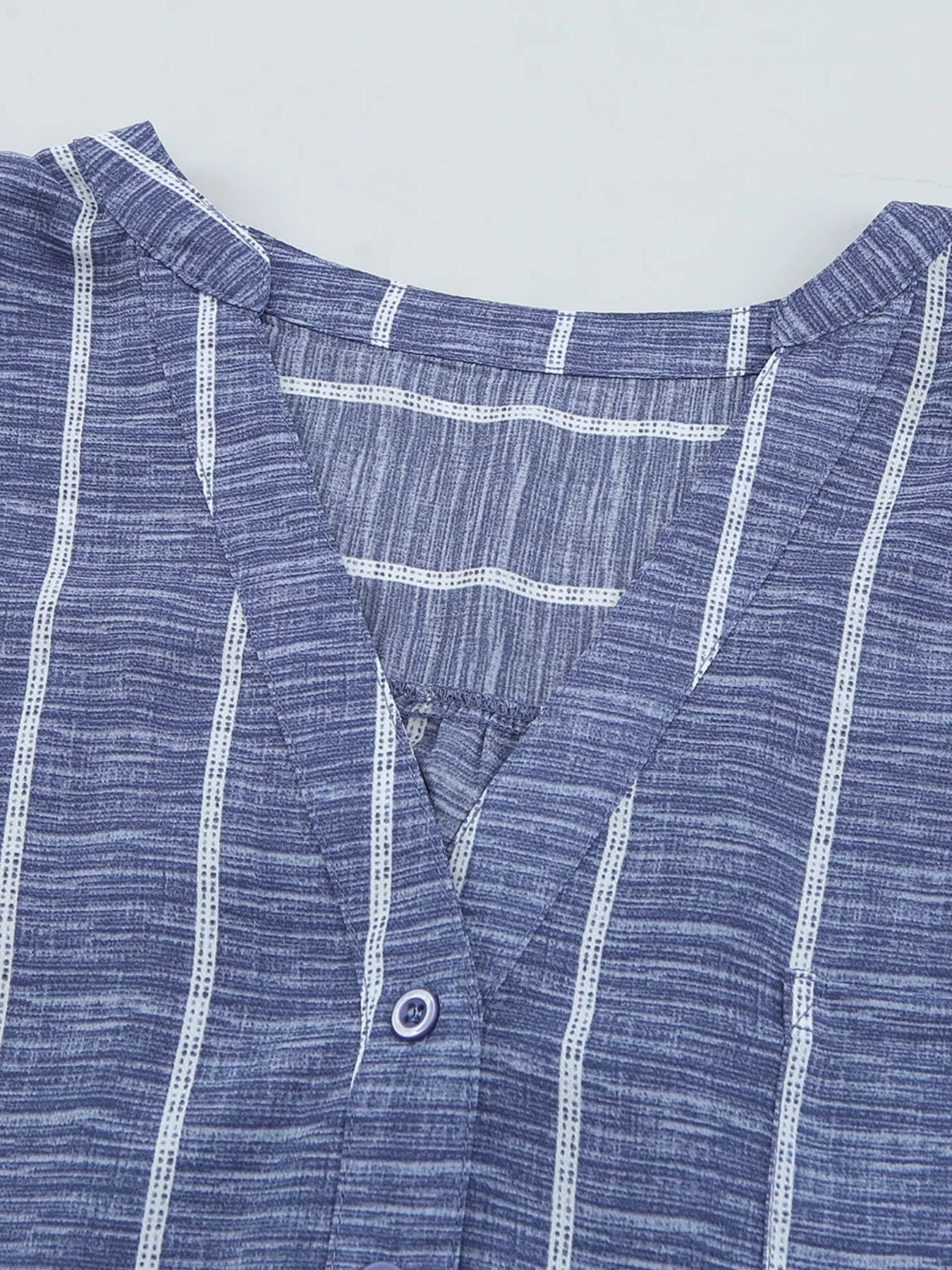 Dusty blue striped V-neck buttoned blouse with a textured fabric.
