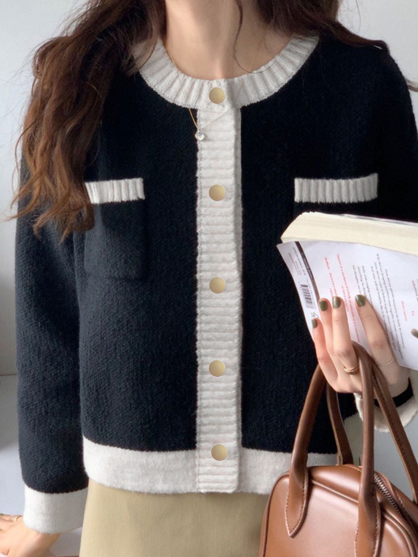 Black acrylic cardigan with contrast trim and gold buttons.