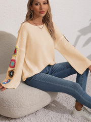 Tan knit sweater with colorful granny square crochet detail on bell sleeves.