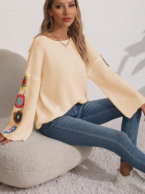 Tan knit sweater with colorful granny square crochet detail on bell sleeves.