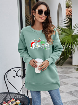 Sage green tunic sweatshirt with "Don't Stop Believing" holiday graphic and Santa hat.