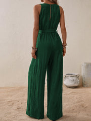 Dark green textured wrap-front wide-leg jumpsuit with belted waist and sleeveless design.