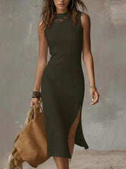 Sleeveless midi dress in sage with a high neckline and side slit, worn by a model holding a straw bag.